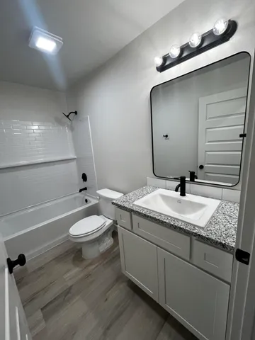 a bathroom with a granite countertop sink mirror vanity and toilet
