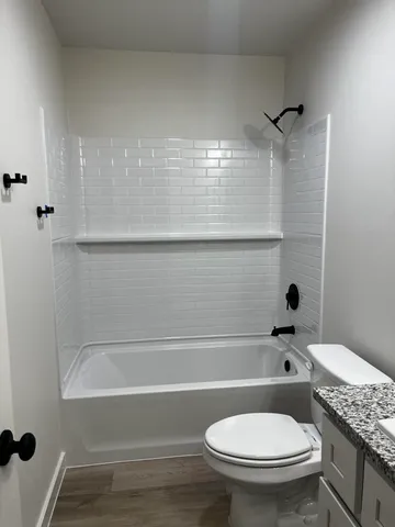 a bathroom with a granite countertop toilet a sink and bathtub