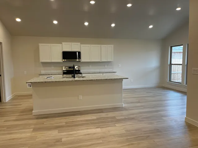 a view of kitchen with stainless steel appliances granite countertop a stove a sink and a microwave