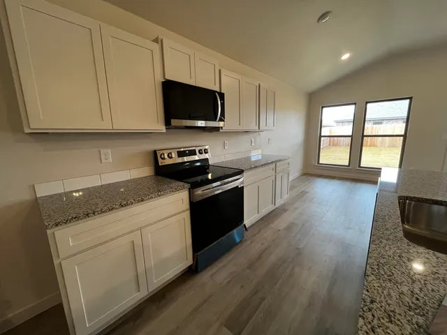 a kitchen with stainless steel appliances granite countertop a stove a sink and a microwave