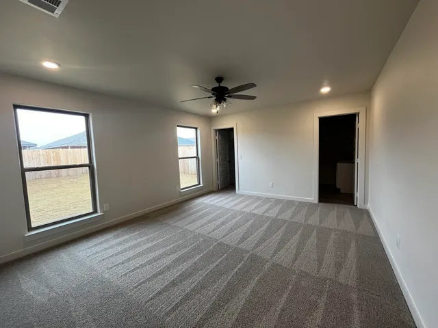 an empty room with windows and ceiling fan