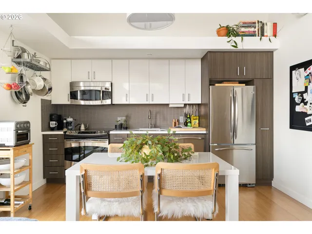 a kitchen with stainless steel appliances a refrigerator a stove a sink dishwasher and white cabinets with wooden floor