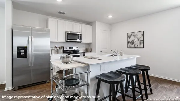 a kitchen with stainless steel appliances a sink a stove a refrigerator with white cabinets and wooden floor