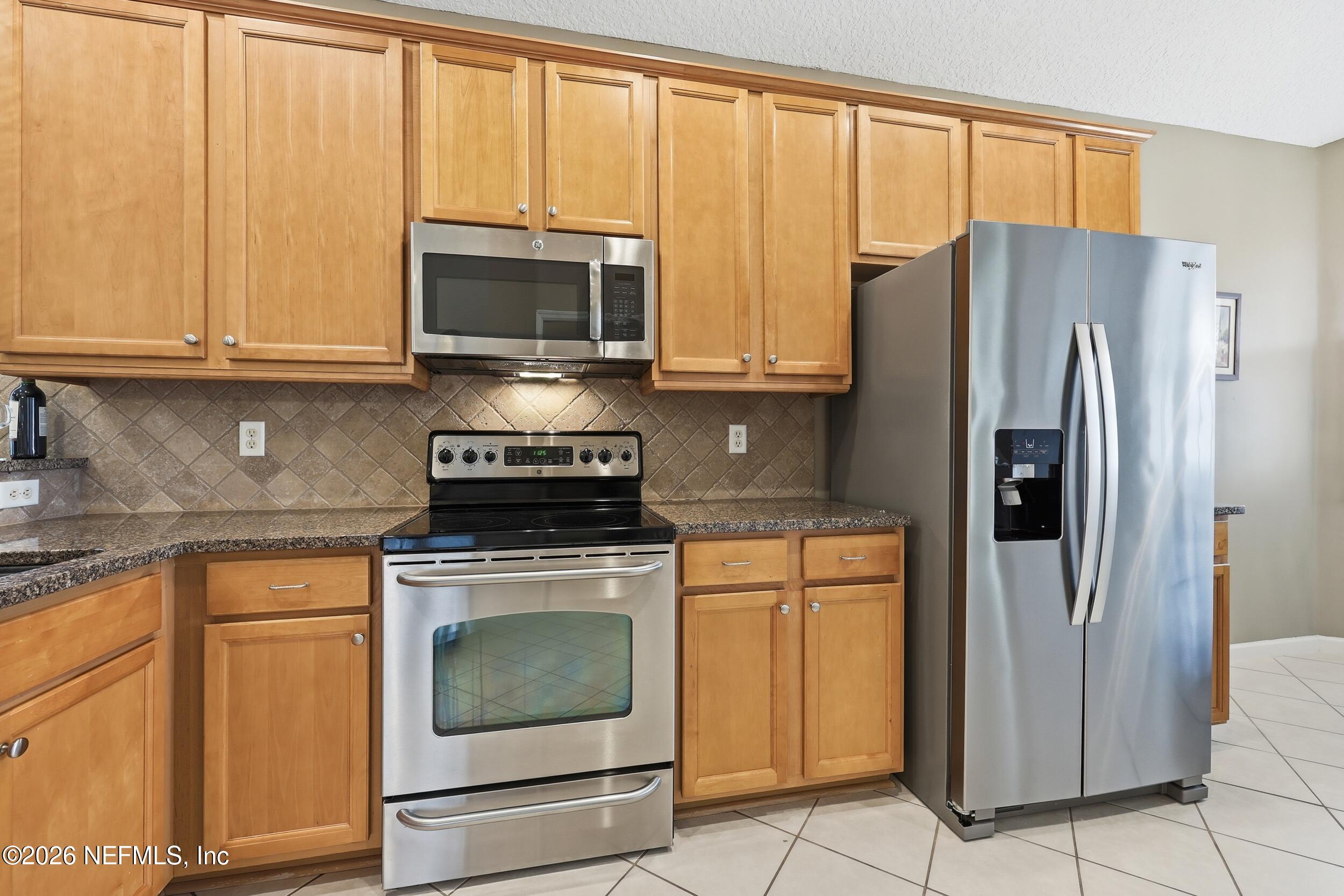 720 Copperhead Circle St. Augustine, FL 32092 - Photo 9 of 65 a kitchen with stainless steel appliances granite countertop a refrigerator stove and microwave