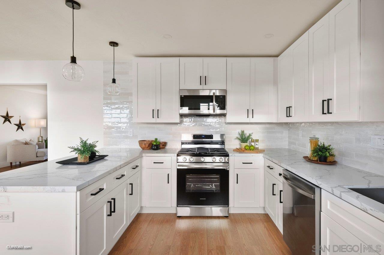 a kitchen with stainless steel appliances a stove a sink a stove a white cabinets a wooden floor and a window
