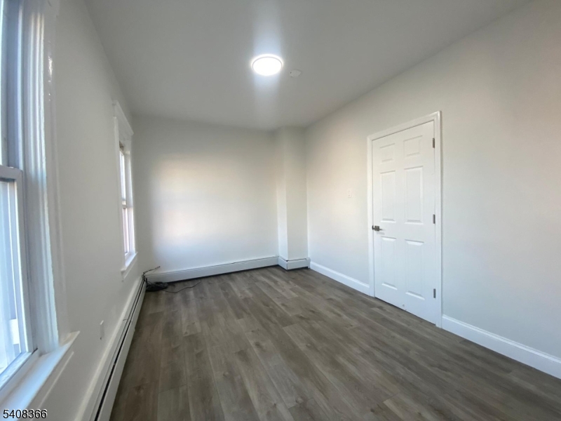 223 John Street Elizabeth, NJ 07202 - Photo 5 of 6 an empty room with wooden floor and windows