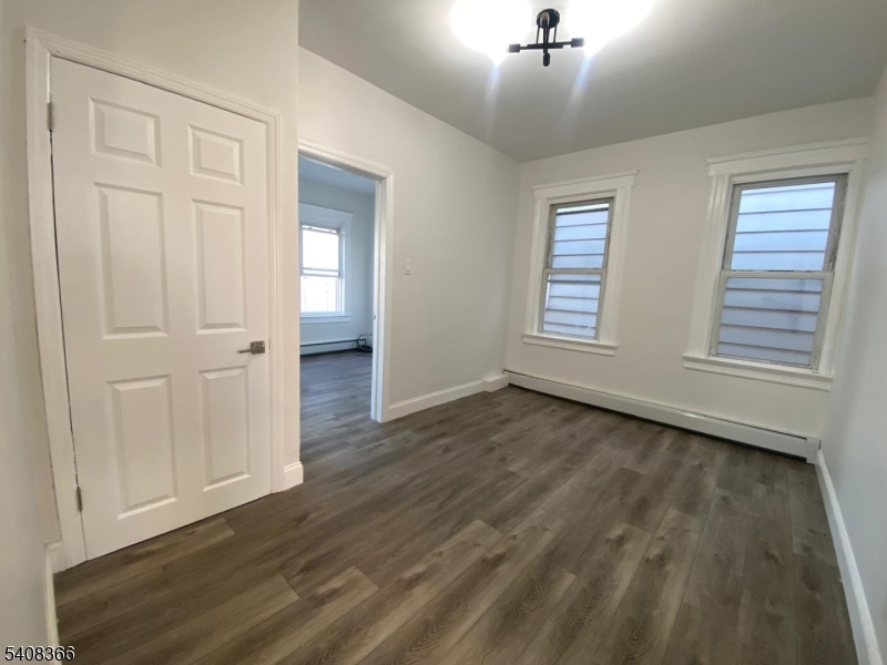 223 John Street Elizabeth, NJ 07202 - Photo 6 of 6 an empty room with wooden floor cabinet and windows