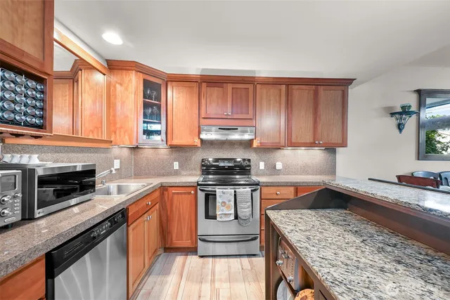 a kitchen with stainless steel appliances granite countertop a stove a sink and a microwave