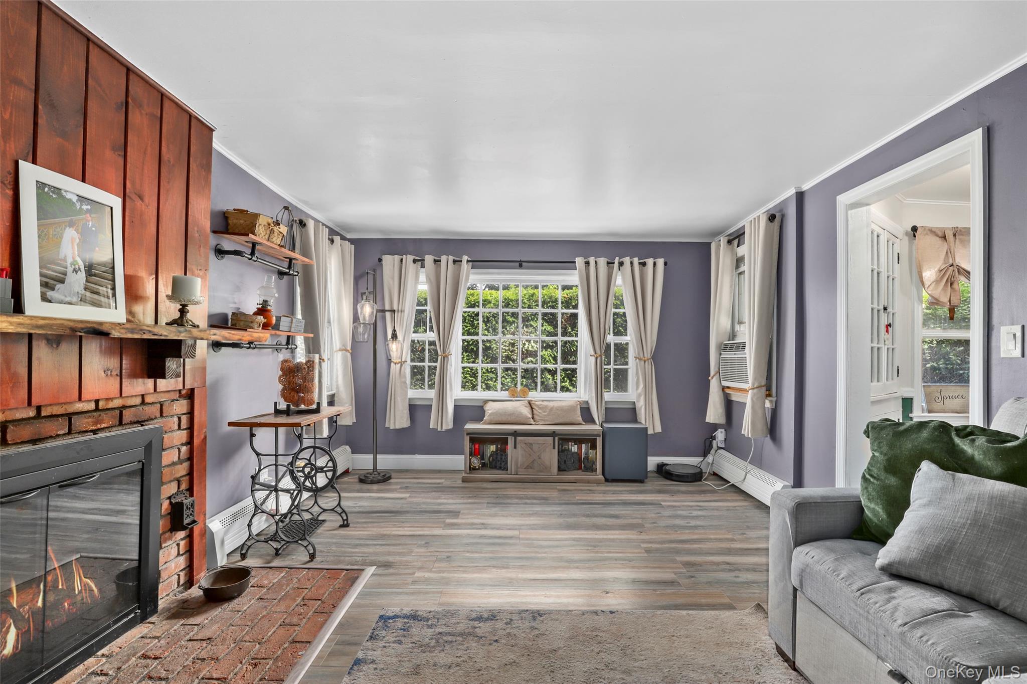 Living room featuring ornamental molding, wood finished floors, and a brick fireplace