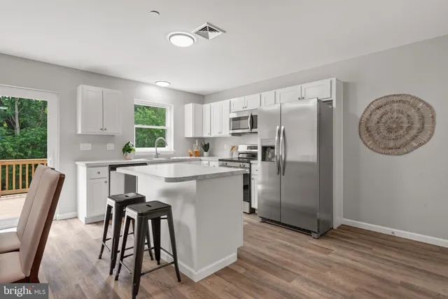 a kitchen with kitchen island a counter top space a sink stainless steel appliances and cabinets