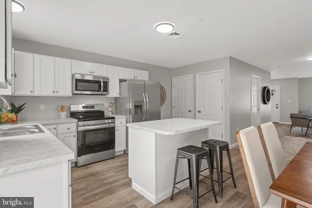 a kitchen with cabinets stainless steel appliances and wooden floor