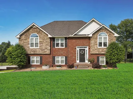 a front view of a house with a yard and trees