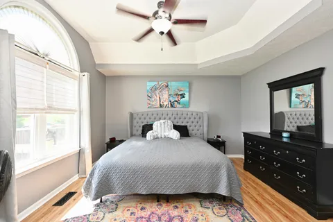 a bedroom with a bed a dresser and a chandelier