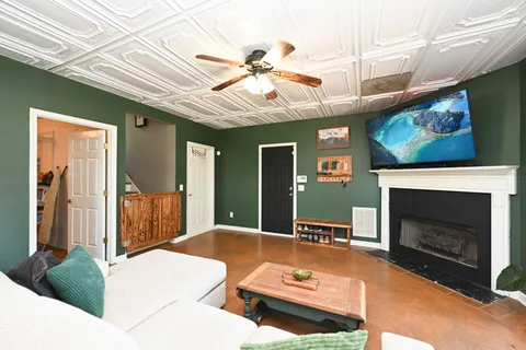 a living room with furniture a fireplace and a ceiling fan