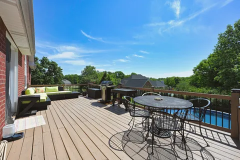 a view of a roof deck with table and chairs couches with wooden floor and fence