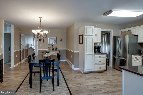 a kitchen with stainless steel appliances kitchen island granite countertop a refrigerator a stove a dining table and chairs with wooden floor