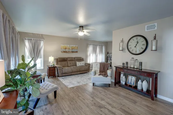 a living room with furniture a clock potted plant and a window