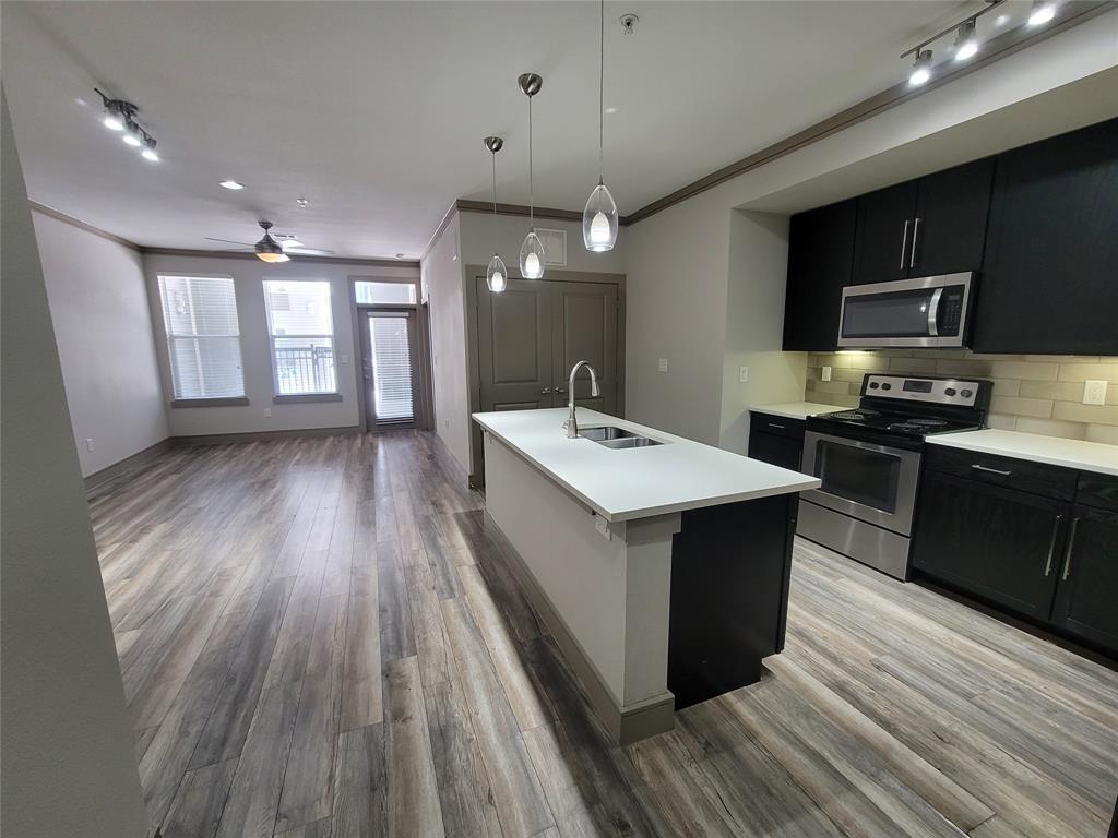 a kitchen with stainless steel appliances a sink wooden floor cabinets and a counter top space