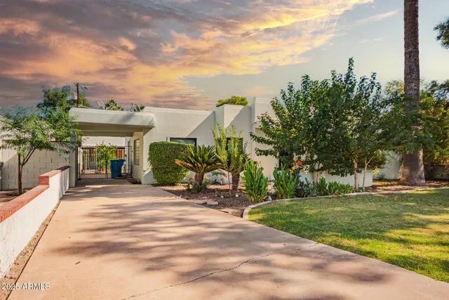 a front view of a house with a garden and trees