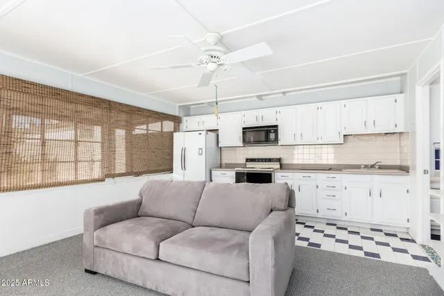 a living room with stainless steel appliances white cabinets and a window