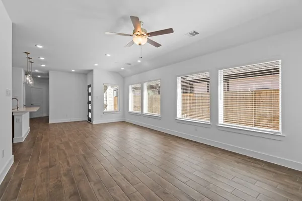 a view of an empty room with a window and wooden floor