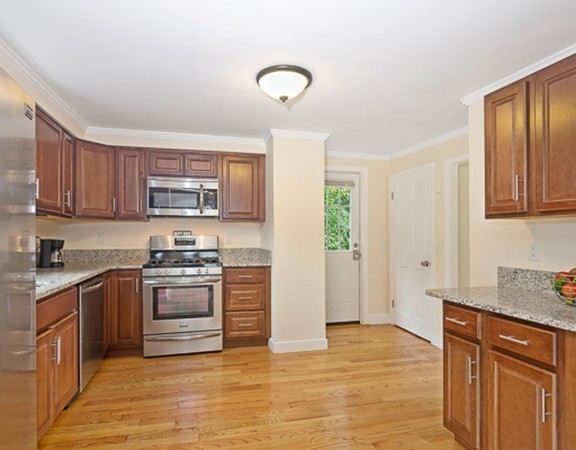 80 Hillcrest Road Waltham, MA 02451 - Photo 2 of 20 a kitchen with stainless steel appliances granite countertop a stove top oven a sink dishwasher and a refrigerator with wooden cabinets