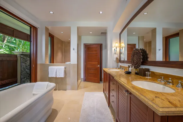 a bathroom with a granite countertop tub sink a large mirror a bathtub and shower
