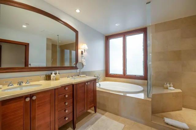 a bathroom with a double vanity sink bathtub and large mirror