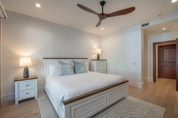a bedroom with a large bed and a lamp on dresser