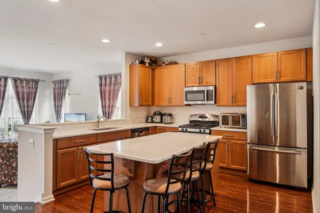 a kitchen with stainless steel appliances granite countertop a stove a refrigerator a sink a dining table and chairs