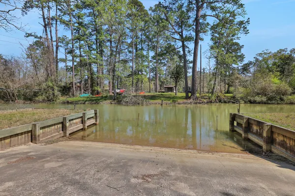 a view of a lake with a yard and trees in the background