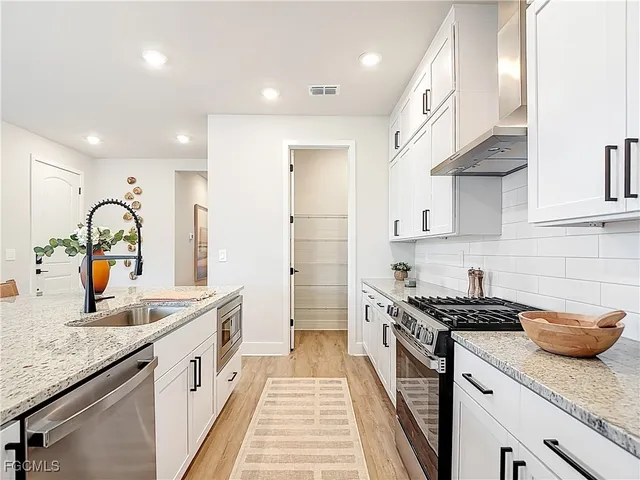a kitchen with granite countertop a sink stainless steel appliances and cabinets
