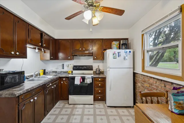 a kitchen with a refrigerator a stove a sink dishwasher and wooden cabinets with wooden floor