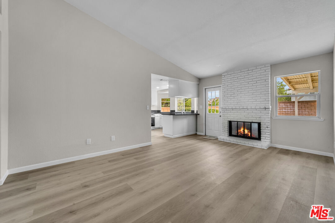 716 East E Avenue Lancaster, CA 93535 - Photo 5 of 17 an empty room with wooden floor a fireplace and windows