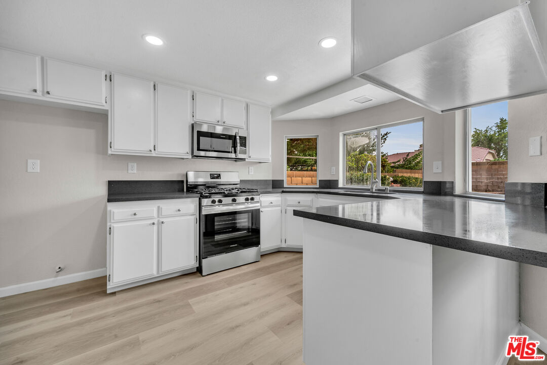 716 East E Avenue Lancaster, CA 93535 - Photo 7 of 17 a kitchen with granite countertop a stove a sink and a refrigerator