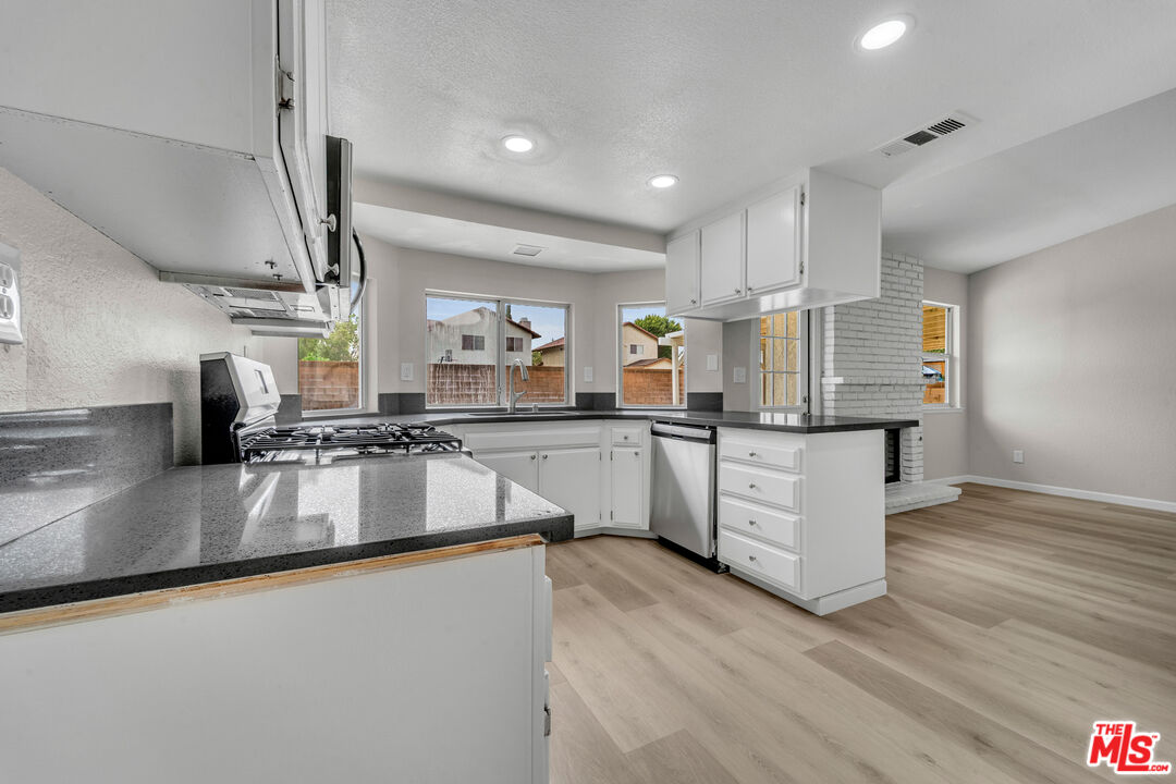 716 East E Avenue Lancaster, CA 93535 - Photo 8 of 17 a large kitchen with kitchen island a large counter top space a sink stainless steel appliances and cabinets