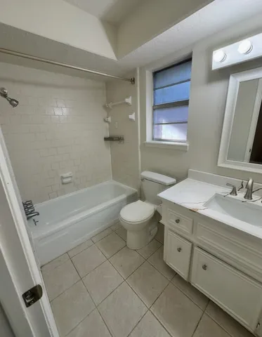 a bathroom with a granite countertop sink a toilet mirror and bathtub