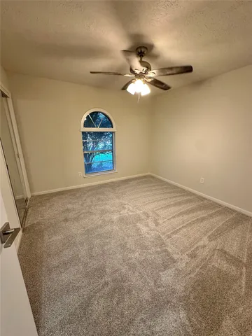 an empty room with a chandelier fan and windows