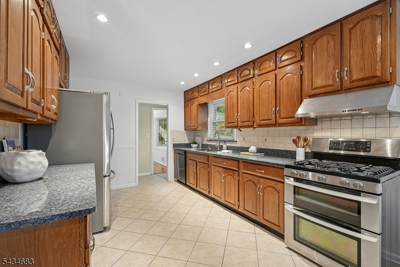 106 Division Avenue Summit, NJ 07901 - Photo 10 of 38 a kitchen with granite countertop wooden cabinets and stainless steel appliances