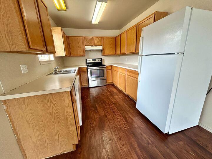 1108 82nd Street, Unit A Lubbock, TX 79423 - Photo 2 of 11 a kitchen with wooden cabinets and white stainless steel appliances