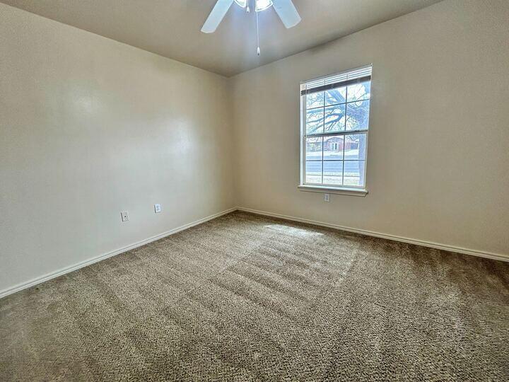 1108 82nd Street, Unit A Lubbock, TX 79423 - Photo 4 of 11 an empty room with a chandelier fan and windows