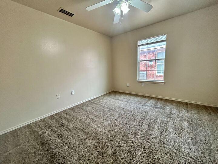1108 82nd Street, Unit A Lubbock, TX 79423 - Photo 6 of 11 an empty room with a chandelier fan and windows