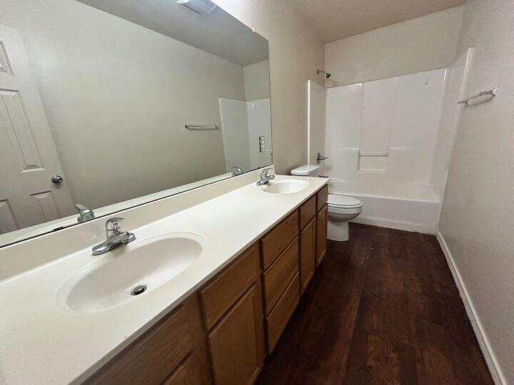 1108 82nd Street, Unit A Lubbock, TX 79423 - Photo 7 of 11 a bathroom with a double vanity sink a toilet and a mirror
