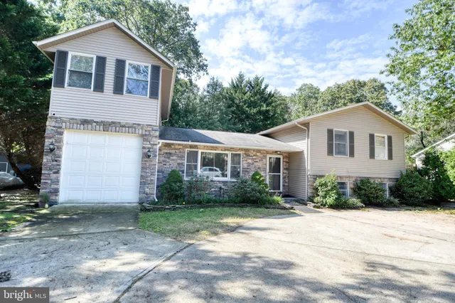 a view of a yard in front of a white house with large windows