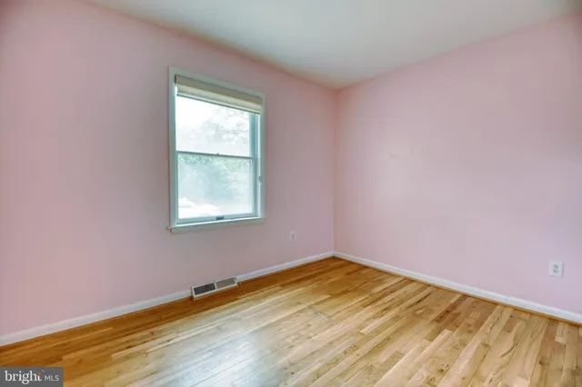 a view of an empty room with a window and wooden floor