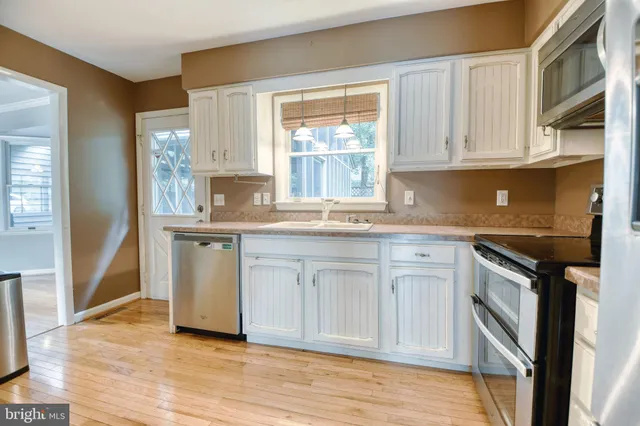 a kitchen with kitchen island granite countertop a sink cabinets stainless steel appliances and a window