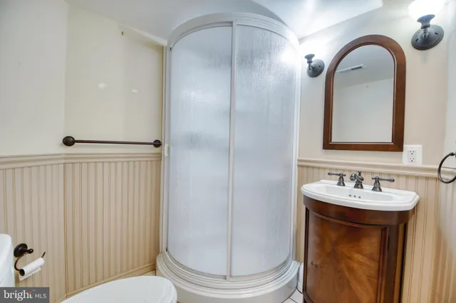 a bathroom with a sink a toilet a mirror and shower