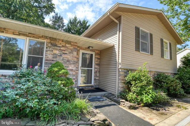 a view of house with potted plants and a bench