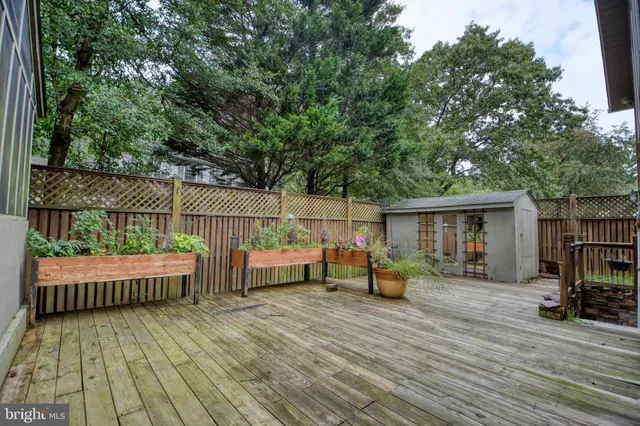 a view of house with deck outdoor seating and trees in the background
