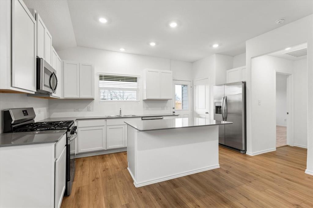 487 Alamito Avenue Kyle, TX 78640 - Photo 12 of 36 a kitchen with stainless steel appliances granite countertop a refrigerator a sink dishwasher a stove and white cabinets with wooden floor